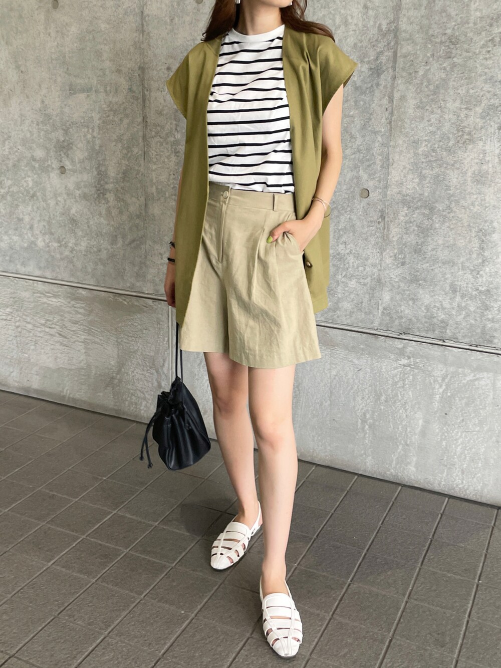 グリーン系のベスト、グリーン系のその他パンツ、ブラック系のショルダーバッグを着用したレディースの夏コーディネートの2枚目の写真