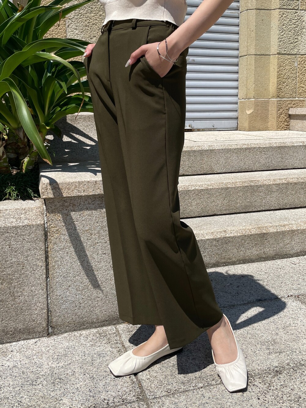 グリーン系のスラックス、ホワイト系のカーディガン/ボレロ、ホワイト系のパンプスを着用したレディースの春コーディネートの2枚目の写真