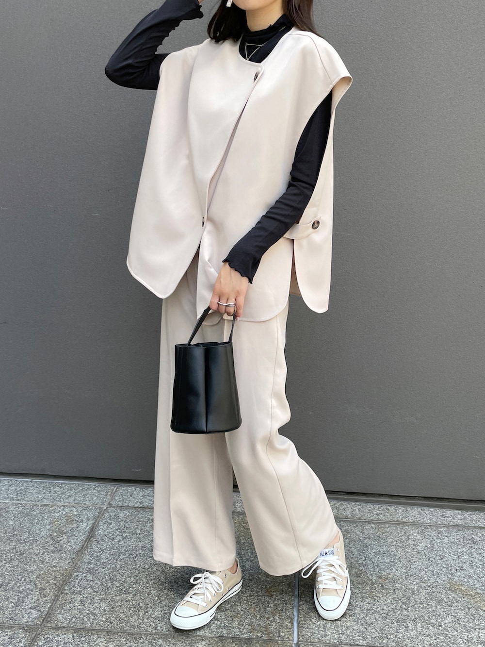 ホワイト系のベスト、ホワイト系のスラックス、ベージュ系のスニーカーを着用したレディースの夏コーディネートの2枚目の写真