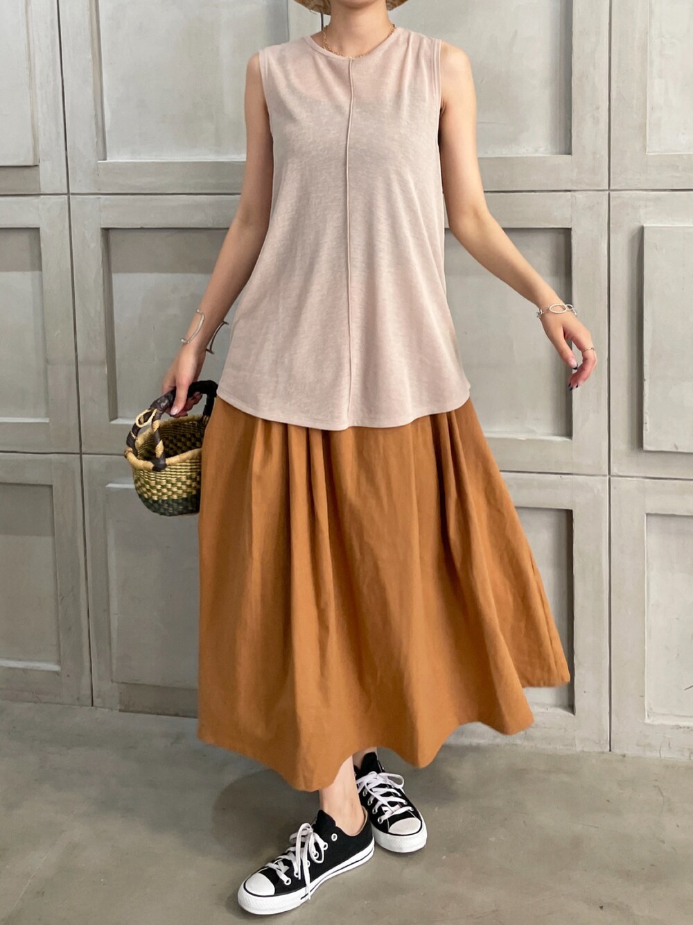 ピンク系のタンクトップ、イエロー系のスカート、ブラック系のスニーカーを着用したレディースの夏コーディネートの2枚目の写真