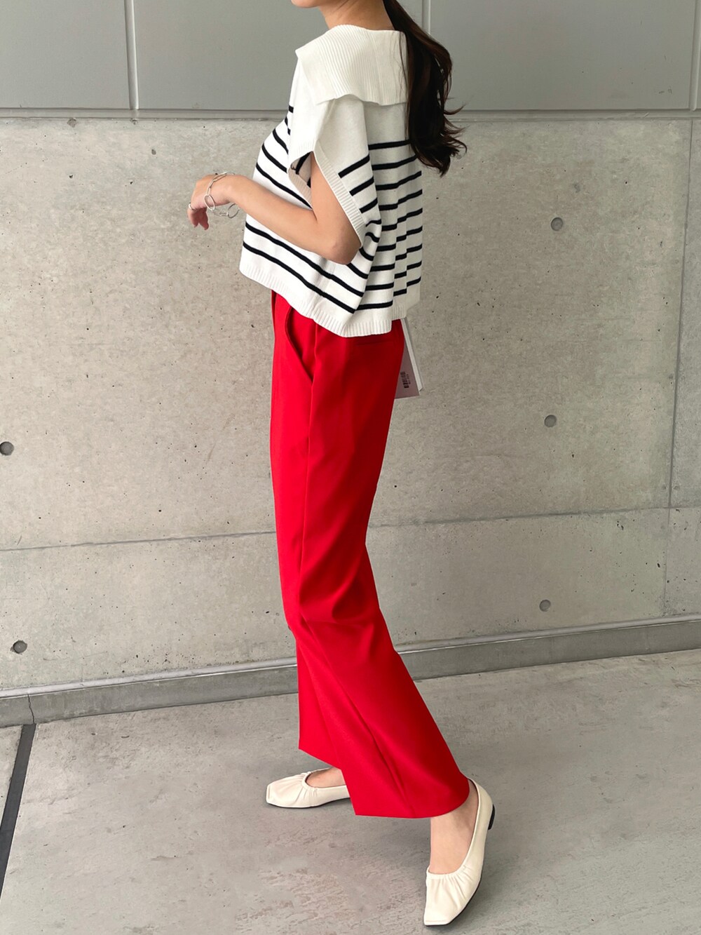 レッド系のスラックス、ホワイト系のパンプス、ホワイト系のベストを着用したレディースの春コーディネートの3枚目の写真