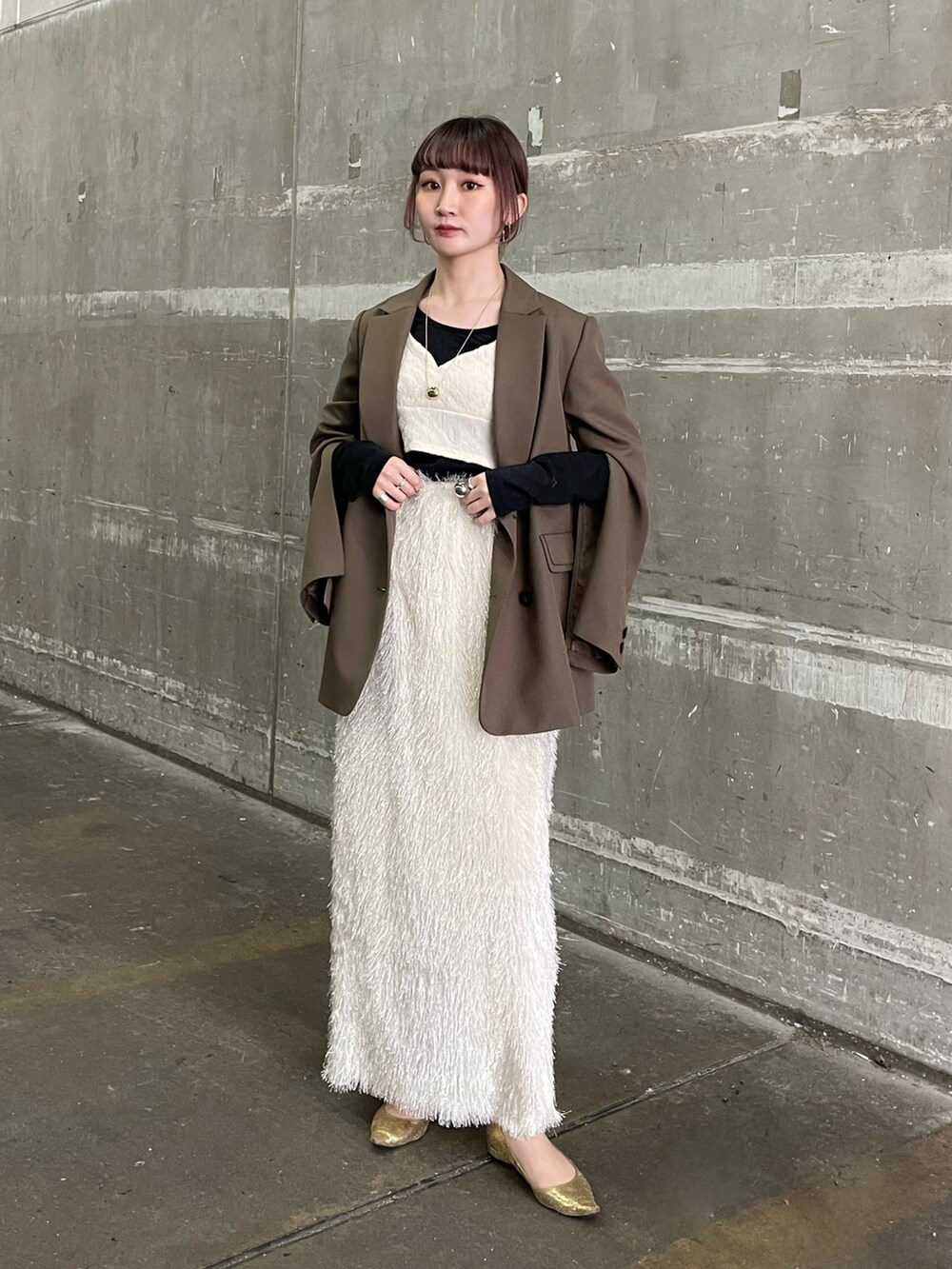 グリーン系のテーラードジャケット、ホワイト系のベスト、ホワイト系のスカートを着用したレディースの春コーディネートの2枚目の写真