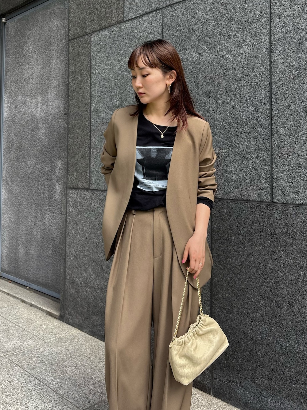 ブラウン系のスラックス、ブラウン系のショルダーバッグ、ブラック系のTシャツ/カットソーを着用したレディースの秋コーディネートの3枚目の写真