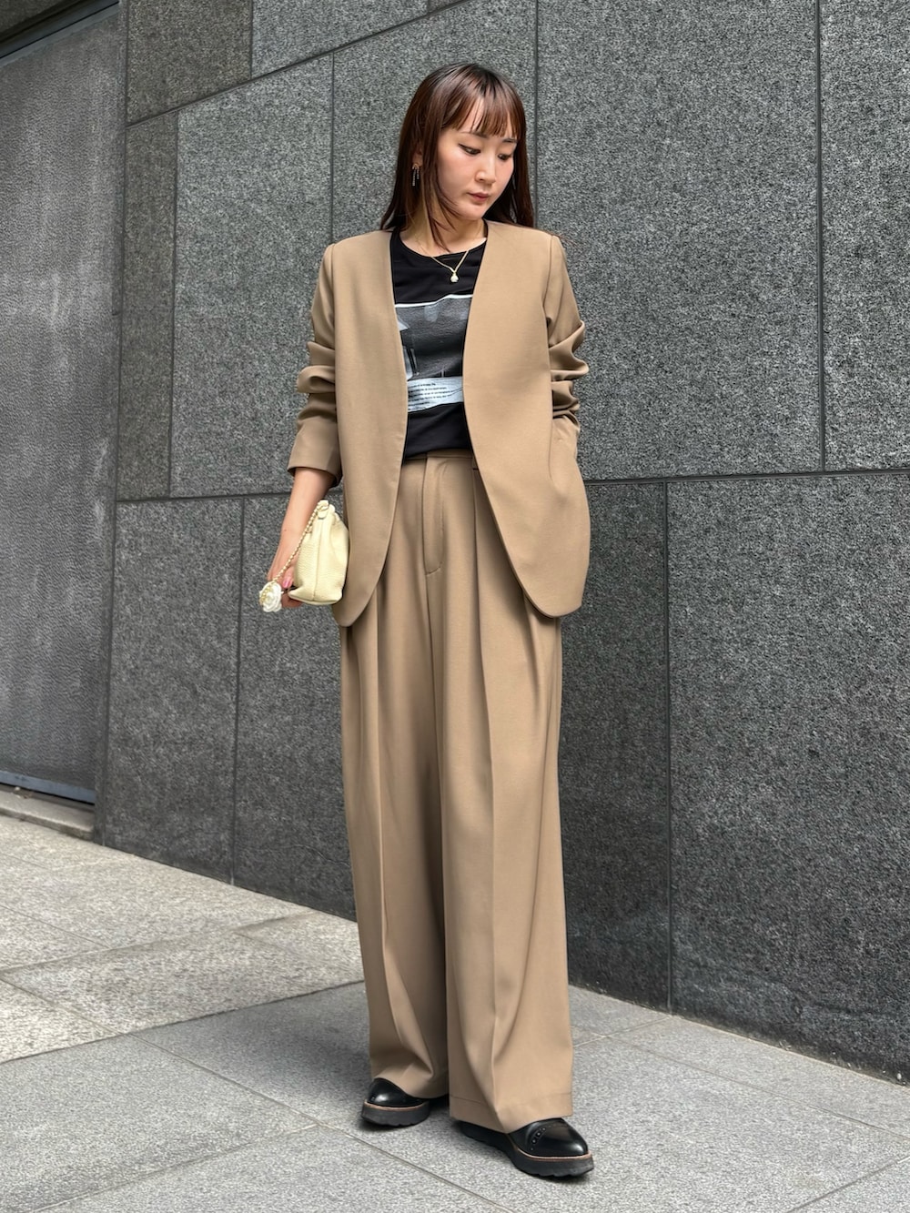 ブラウン系のスラックス、ブラウン系のショルダーバッグ、ブラック系のTシャツ/カットソーを着用したレディースの秋コーディネートの2枚目の写真