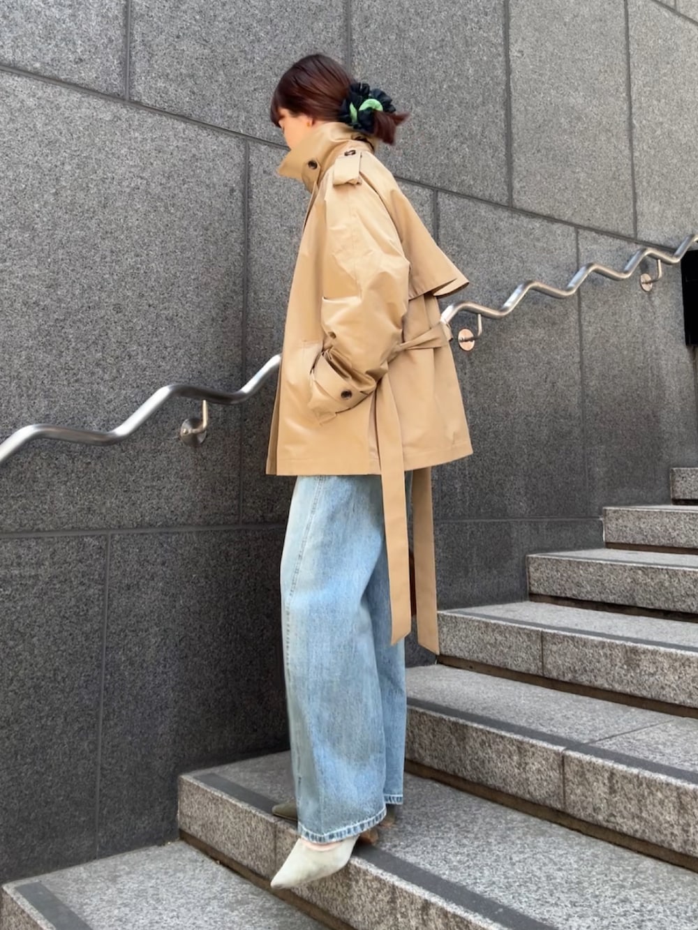 ベージュ系のトレンチコート、ブラウン系のショルダーバッグ、ブルー系のデニムパンツを着用したレディースの冬コーディネートの3枚目の写真