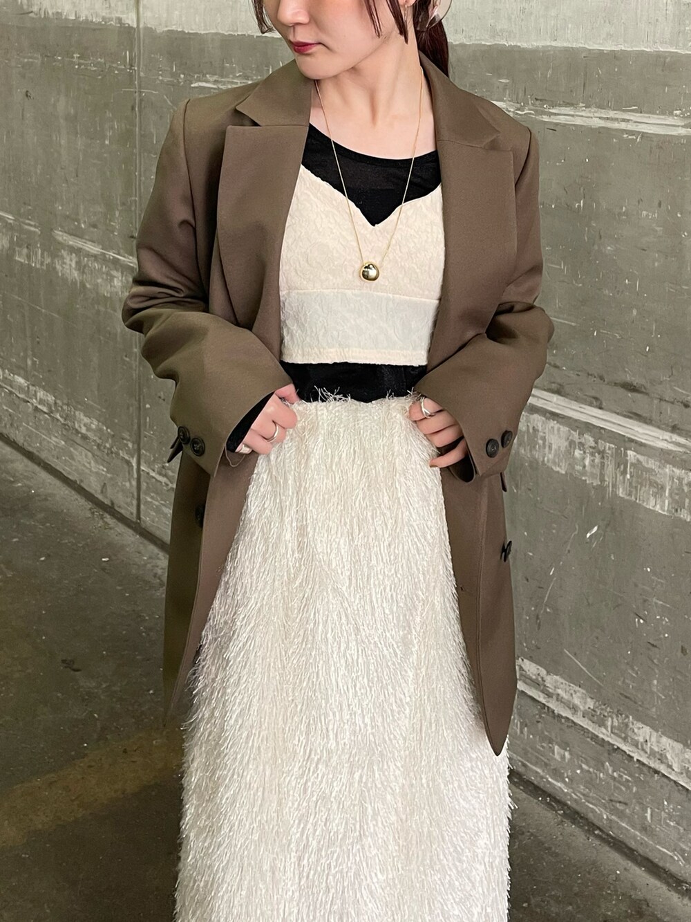 グリーン系のテーラードジャケット、ホワイト系のベスト、ホワイト系のスカートを着用したレディースの春コーディネートの3枚目の写真