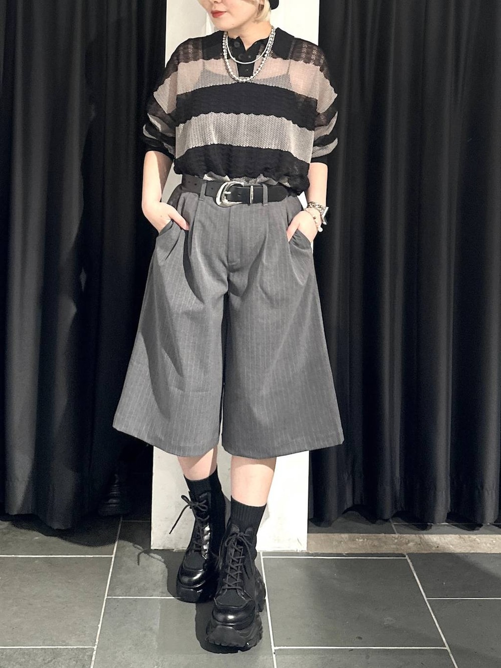 ブラック系のブーツ、グレー系のポロシャツ、グレー系のスラックスを着用したレディースの春コーディネートの3枚目の写真