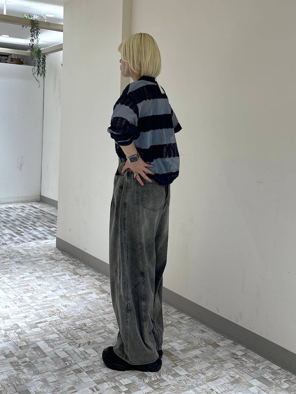 ブラック系のスニーカー、ブラック系のデニムパンツ、ブルー系のポロシャツを着用したレディースの春コーディネートの3枚目の写真