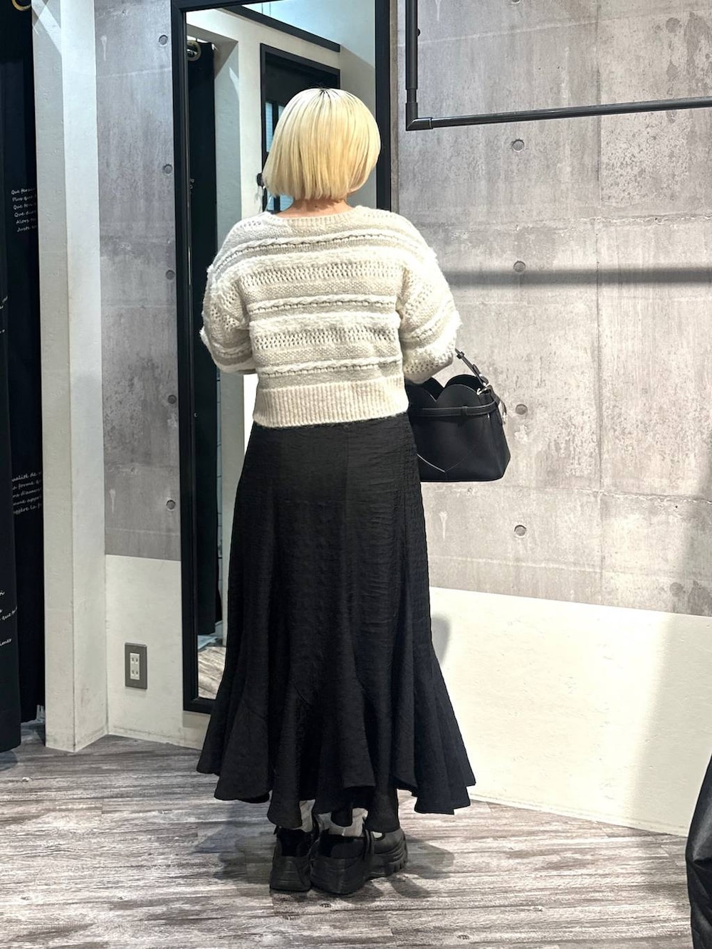 ブラック系のショルダーバッグ、ブラック系のスカート、ホワイト系のニット/セーターを着用したレディースの冬コーディネートの2枚目の写真