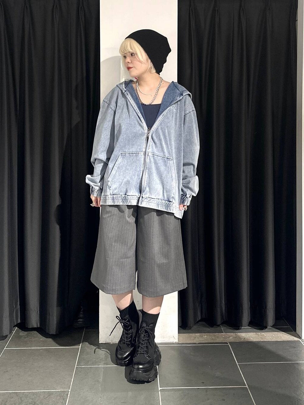 ブラック系のブーツ、ブルー系のパーカー、グレー系のスラックスを着用したレディースの春コーディネートの2枚目の写真