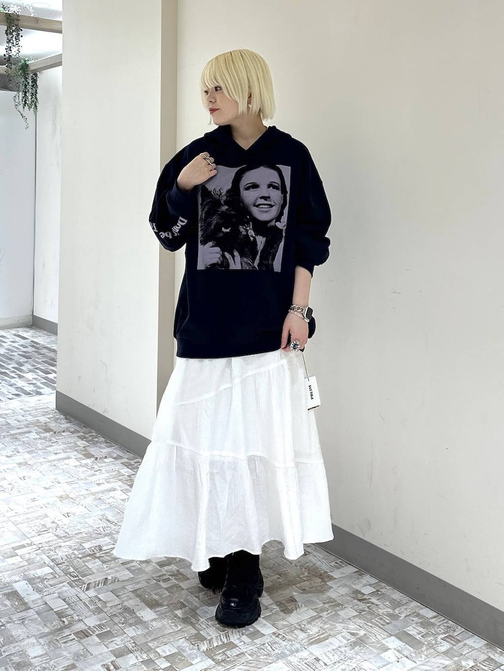 ブラック系のスニーカー、ホワイト系のスカート、ブルー系のパーカーを着用したレディースの春コーディネートの3枚目の写真