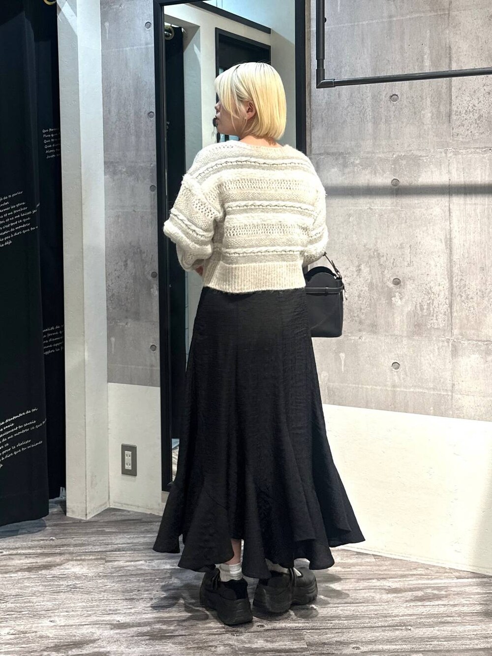 ブラック系のショルダーバッグ、ブラック系のスカート、ホワイト系のニット/セーターを着用したレディースの冬コーディネートの3枚目の写真