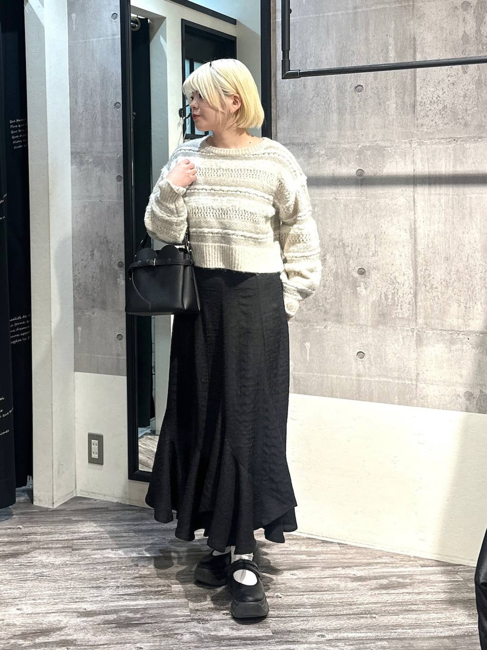 ブラック系のショルダーバッグ、ブラック系のスカート、ホワイト系のニット/セーターを着用したレディースの冬コーディネートの4枚目の写真