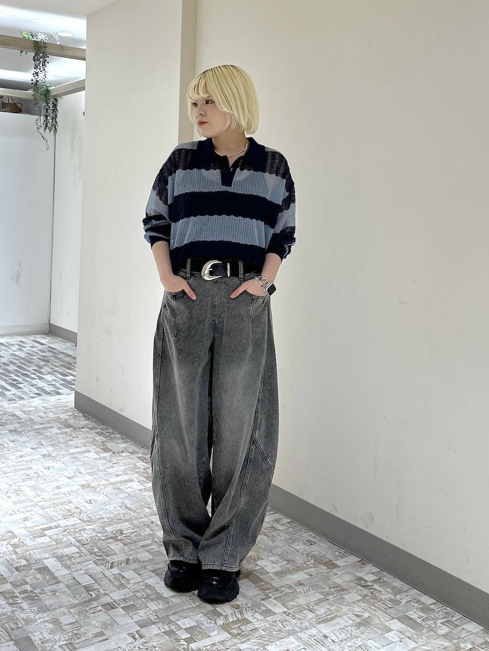 ブラック系のスニーカー、ブラック系のデニムパンツ、ブルー系のポロシャツを着用したレディースの春コーディネートの2枚目の写真