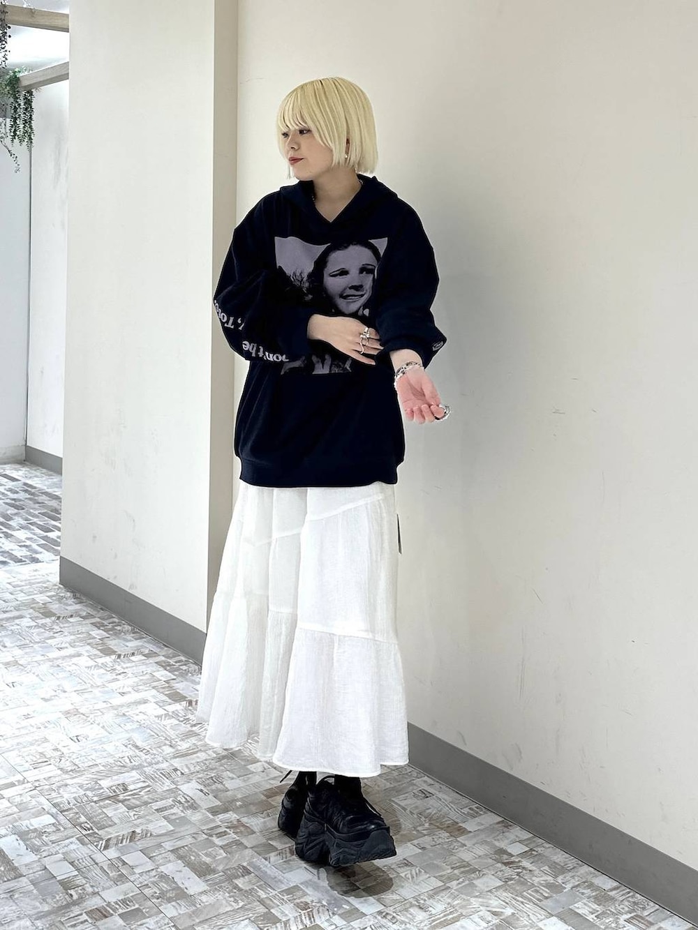 ブラック系のスニーカー、ホワイト系のスカート、ブルー系のパーカーを着用したレディースの春コーディネートの2枚目の写真