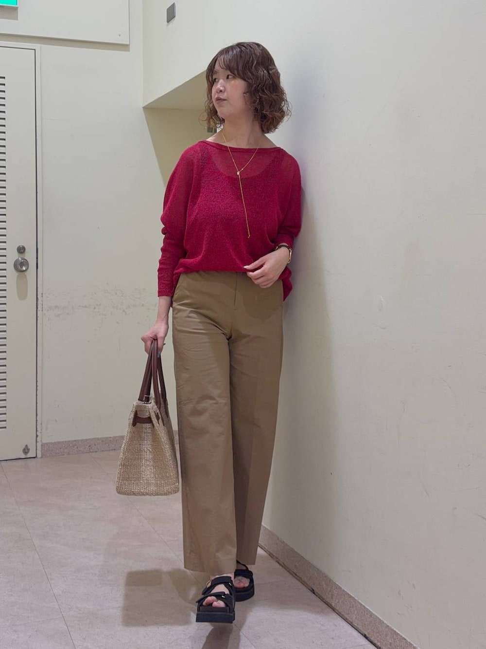 ベージュ系のその他パンツ、レッド系のニット/セーター、ベージュ系のかごバッグを着用したレディースの春コーディネートの2枚目の写真