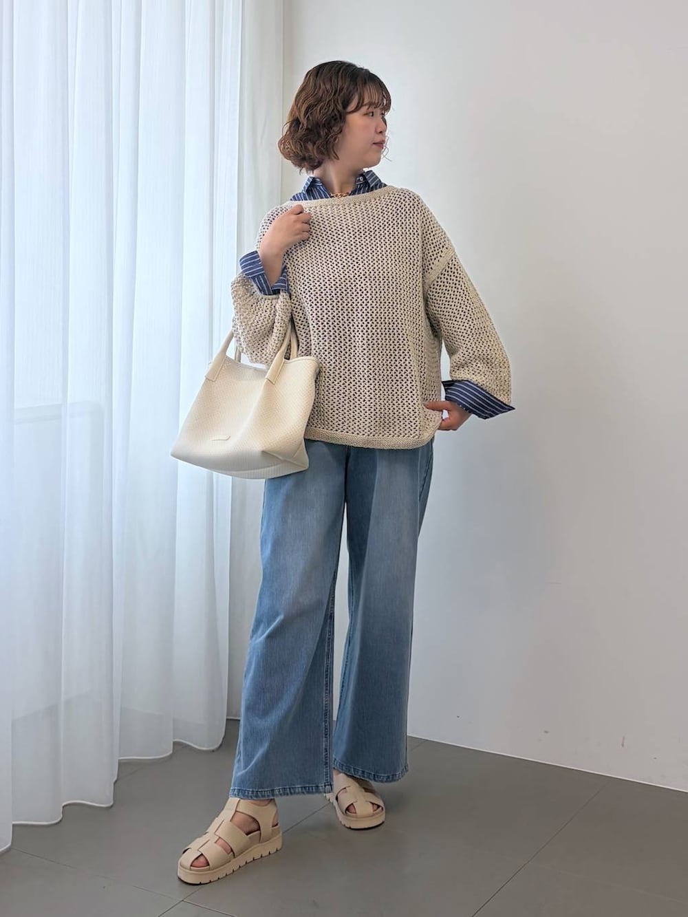 ベージュ系のニット/セーター、ブルー系のデニムパンツ、ホワイト系のトートバッグを着用したレディースの冬コーディネートの3枚目の写真