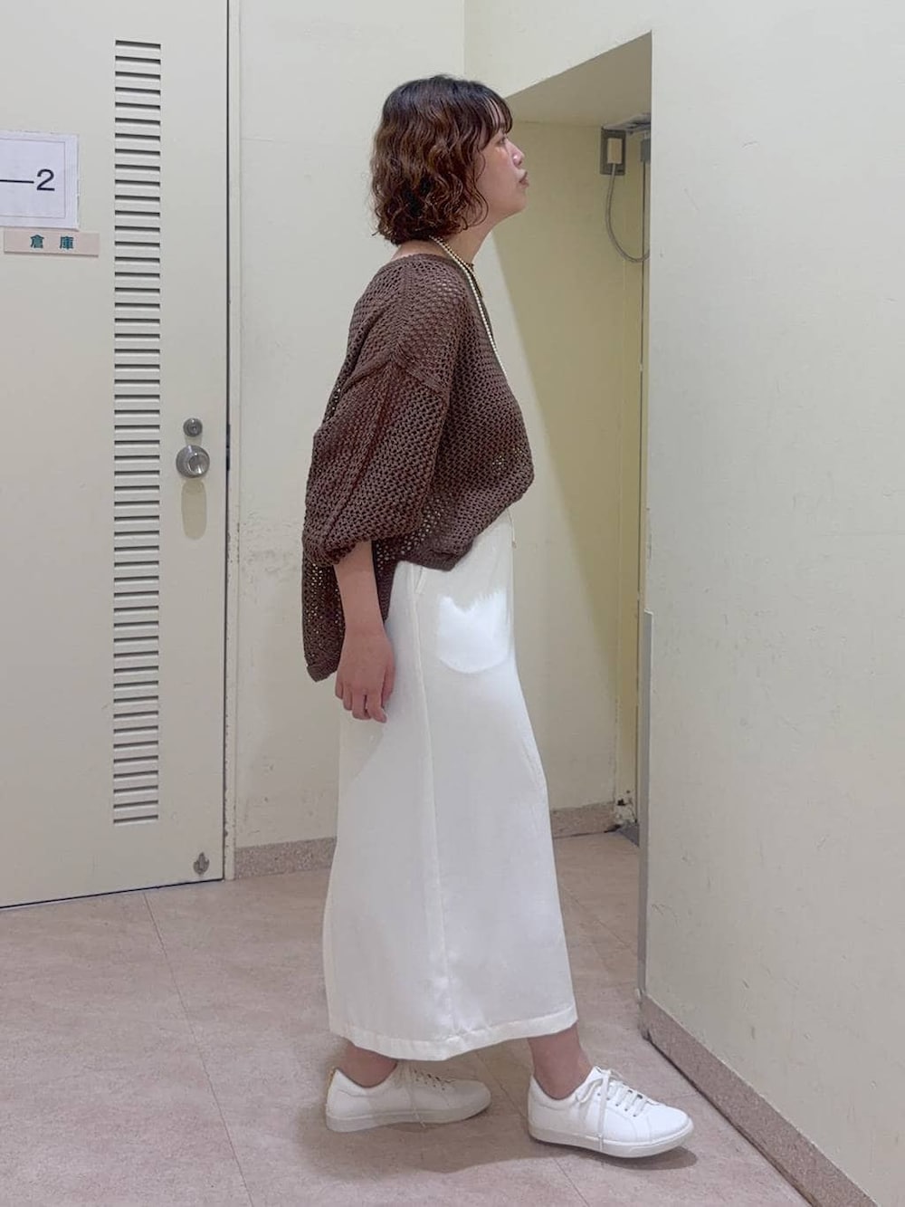 ブラウン系のニット/セーター、ブラック系のタンクトップ、ホワイト系のスニーカーを着用したレディースの冬コーディネートの4枚目の写真