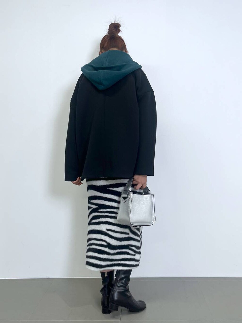 シルバー系のハンドバッグ、ブラック系のブーツ、ブラック系のTシャツ/カットソーを着用したレディースの秋コーディネートの3枚目の写真