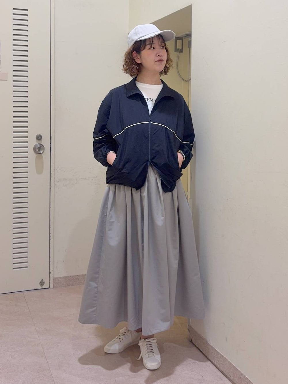 ホワイト系のTシャツ/カットソー、グレー系のスカート、ブルー系のナイロンジャケットを着用したレディースの冬コーディネートの2枚目の写真