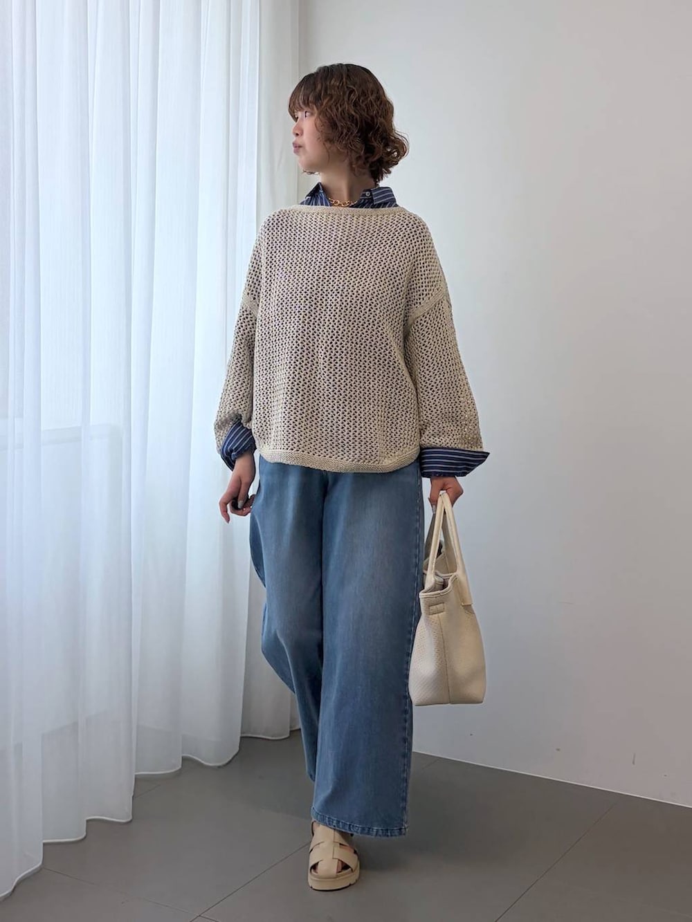 ベージュ系のニット/セーター、ブルー系のデニムパンツ、ホワイト系のトートバッグを着用したレディースの冬コーディネートの4枚目の写真