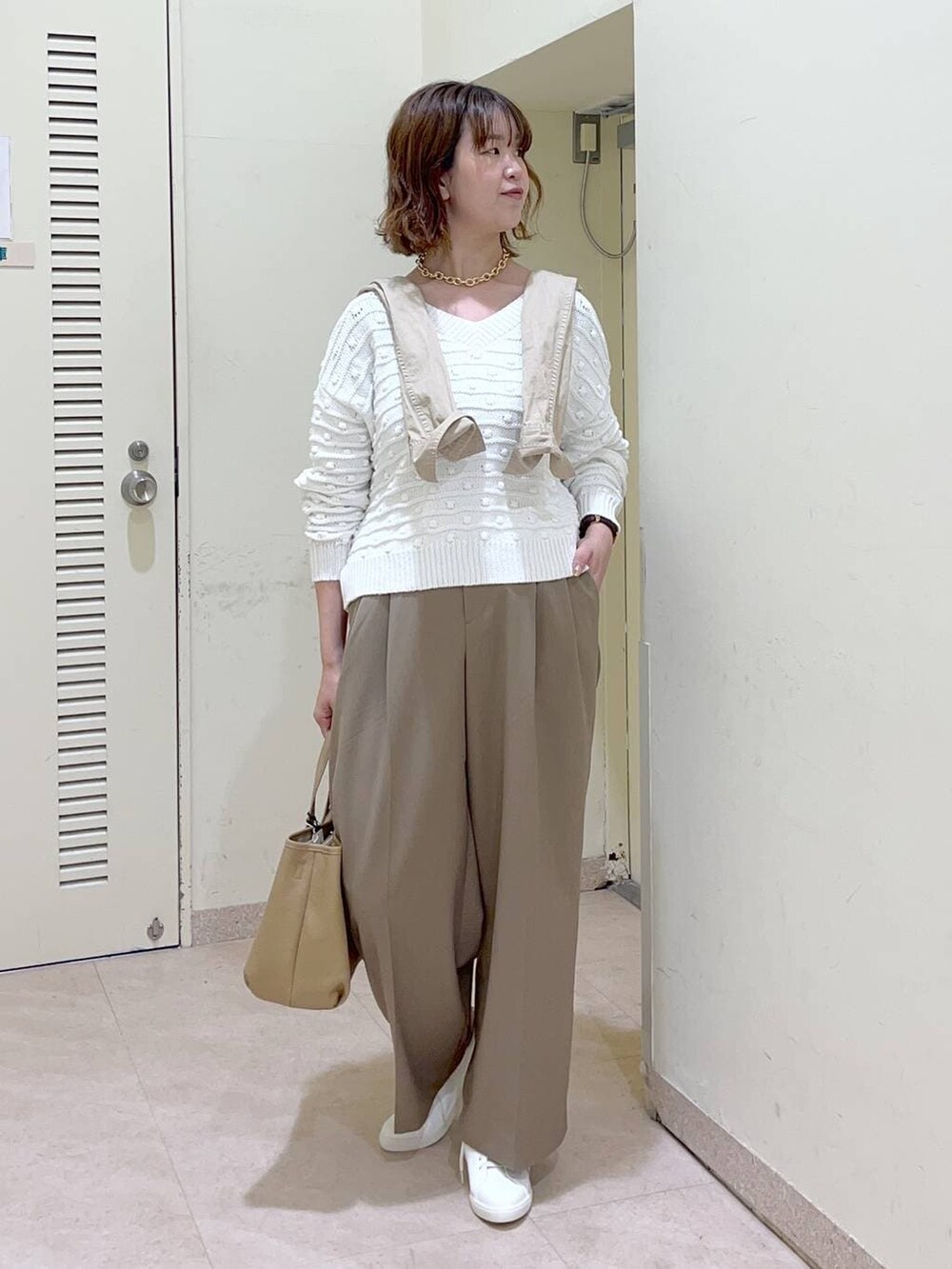 ホワイト系のニット/セーター、ホワイト系のスニーカー、イエロー系のトートバッグを着用したレディースの冬コーディネートの2枚目の写真