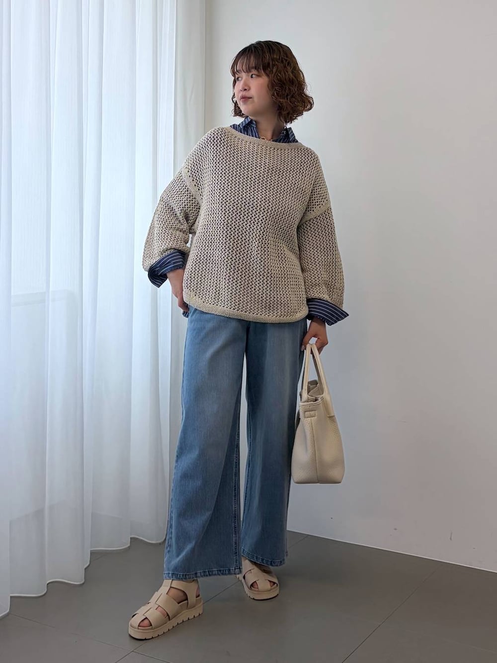 ベージュ系のニット/セーター、ブルー系のデニムパンツ、ホワイト系のトートバッグを着用したレディースの冬コーディネートの2枚目の写真