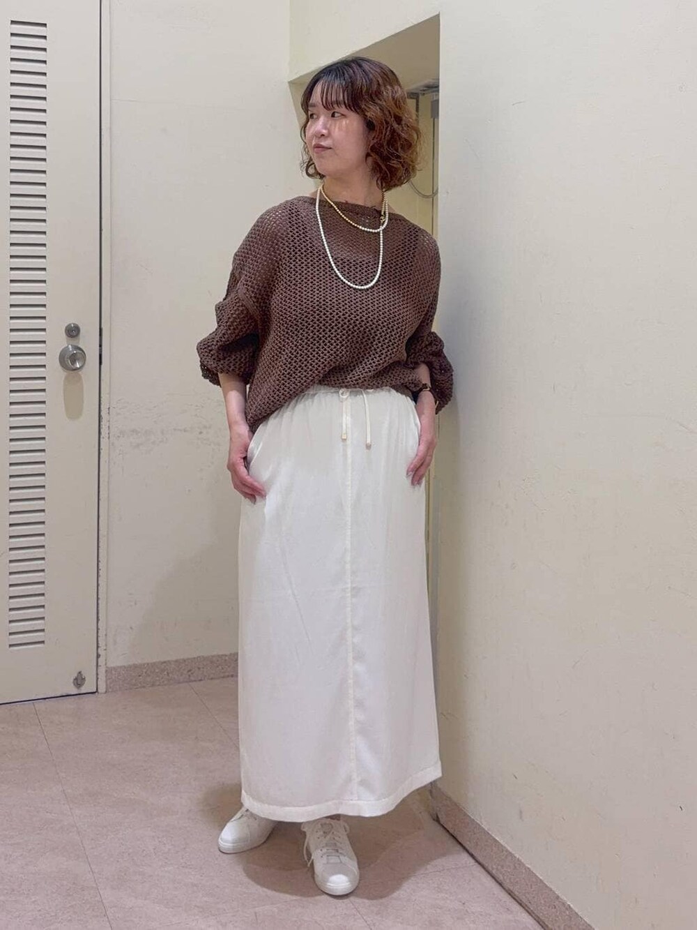 ブラウン系のニット/セーター、ブラック系のタンクトップ、ホワイト系のスニーカーを着用したレディースの冬コーディネートの2枚目の写真