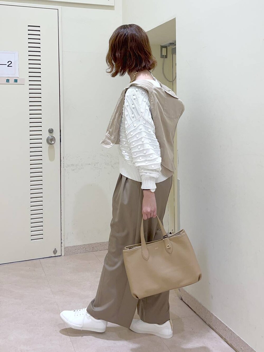 ホワイト系のニット/セーター、ホワイト系のスニーカー、イエロー系のトートバッグを着用したレディースの冬コーディネートの3枚目の写真