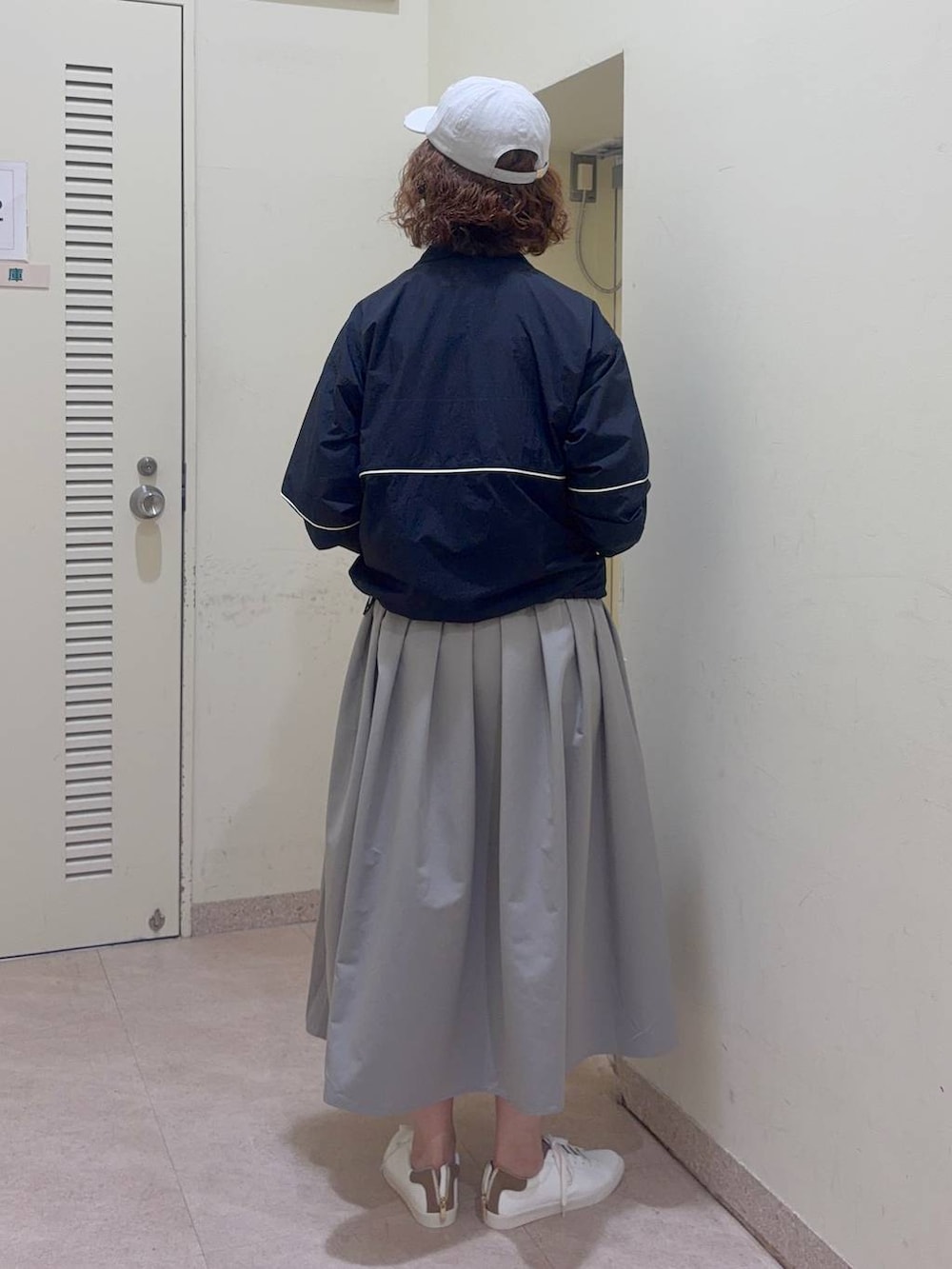 ホワイト系のTシャツ/カットソー、グレー系のスカート、ブルー系のナイロンジャケットを着用したレディースの冬コーディネートの3枚目の写真