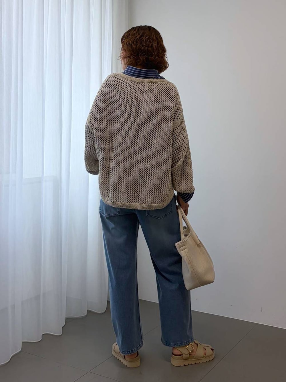 ベージュ系のニット/セーター、ブルー系のデニムパンツ、ホワイト系のトートバッグを着用したレディースの冬コーディネートの6枚目の写真