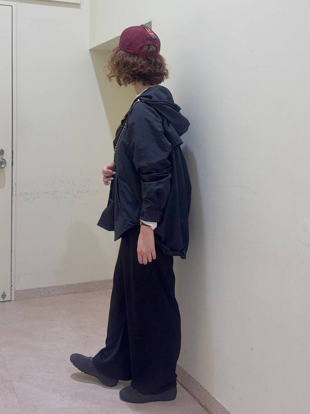 ブラック系のスラックス、ホワイト系のTシャツ/カットソー、ブラック系のマウンテンパーカーを着用したレディースの冬コーディネートの4枚目の写真