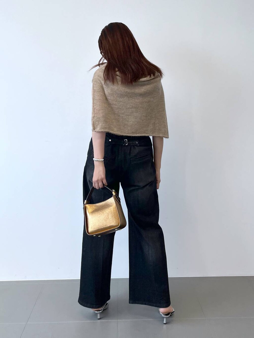 シルバー系のパンプス、ブラック系のデニムパンツ、ベージュ系のニット/セーターを着用したレディースの夏コーディネートの3枚目の写真