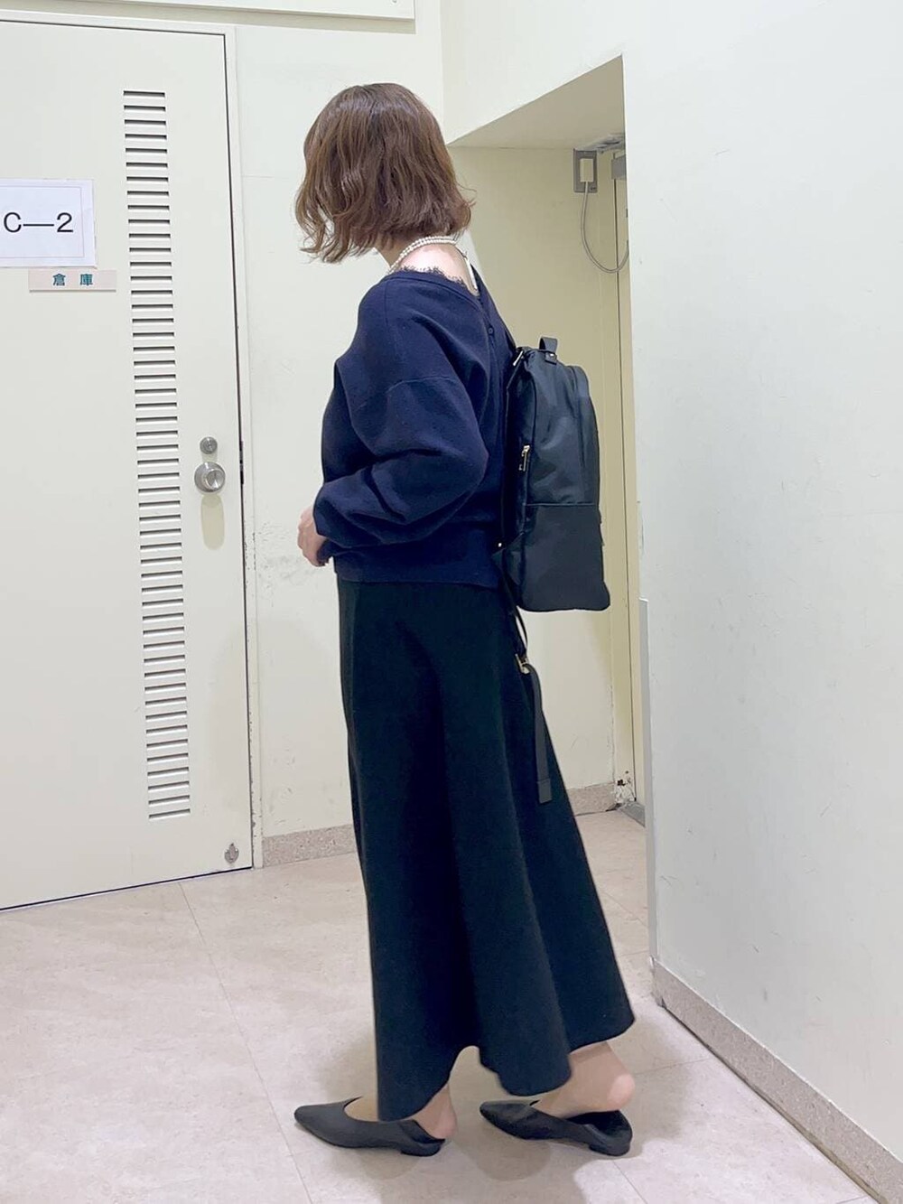 ブラック系のバックパック/リュック、ブラック系のスカート、ブルー系のカーディガン/ボレロを着用したレディースの冬コーディネートの3枚目の写真