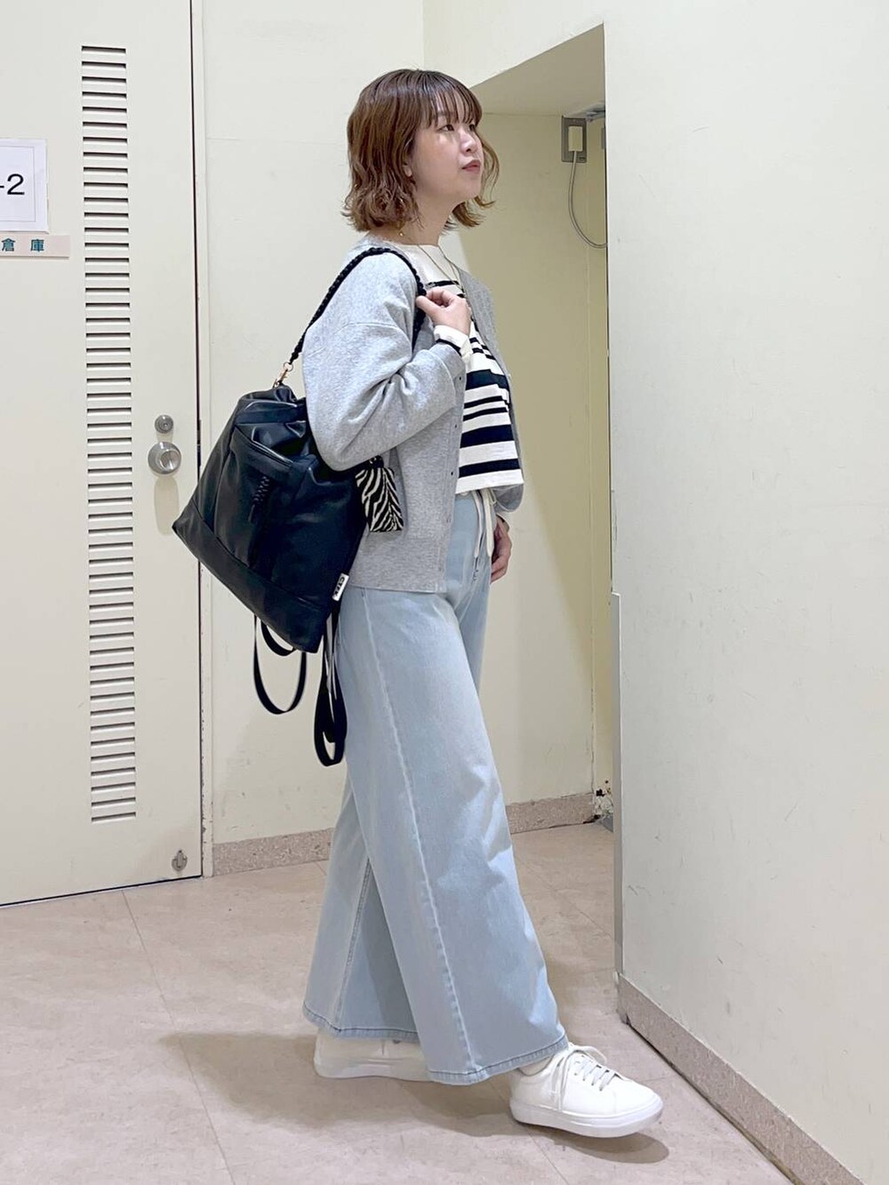 ブラック系のバックパック/リュック、グレー系のカーディガン/ボレロ、ホワイト系のTシャツ/カットソーを着用したレディースの冬コーディネートの3枚目の写真