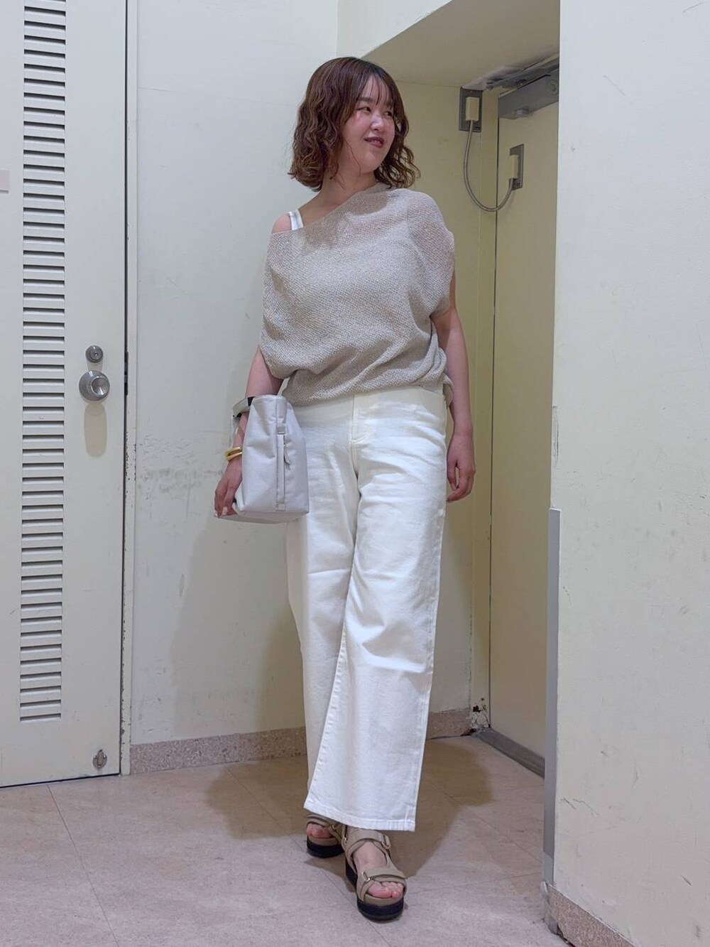 ホワイト系のデニムパンツ、ホワイト系のトートバッグ、ホワイト系のタンクトップを着用したレディースの夏コーディネートの2枚目の写真