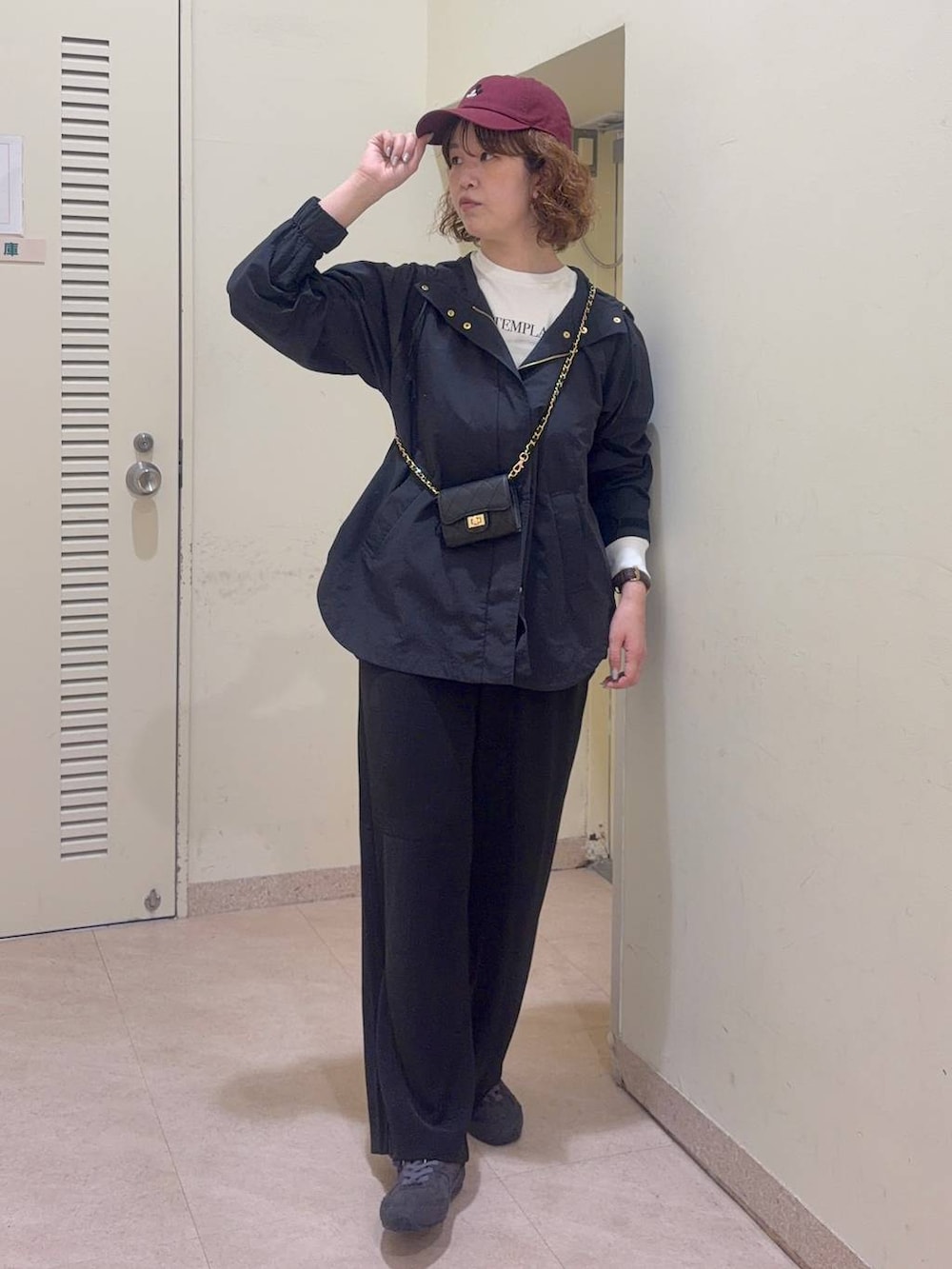 ブラック系のスラックス、ホワイト系のTシャツ/カットソー、ブラック系のマウンテンパーカーを着用したレディースの冬コーディネートの2枚目の写真