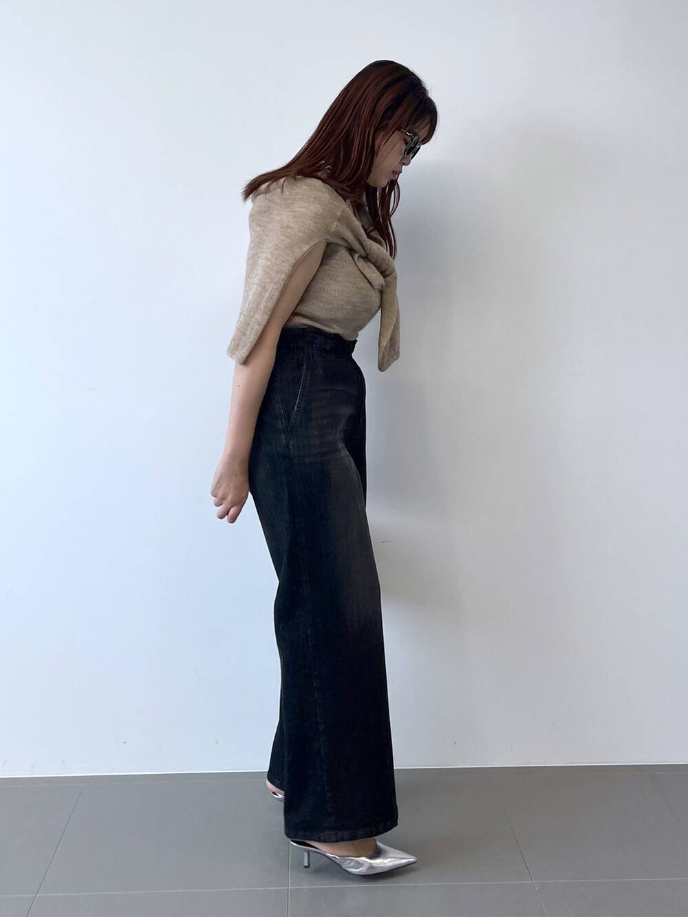 シルバー系のパンプス、ブラック系のデニムパンツ、ベージュ系のニット/セーターを着用したレディースの夏コーディネートの2枚目の写真