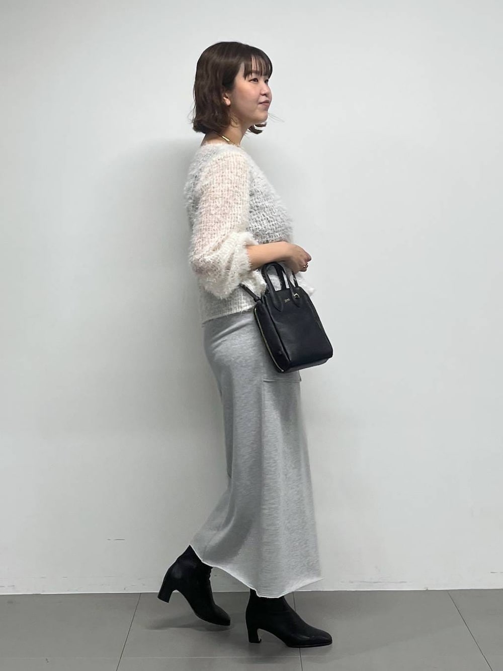 ブラック系のブーツ、ホワイト系のシャツ/ブラウス、ブラック系のショルダーバッグを着用したレディースの冬コーディネートの4枚目の写真