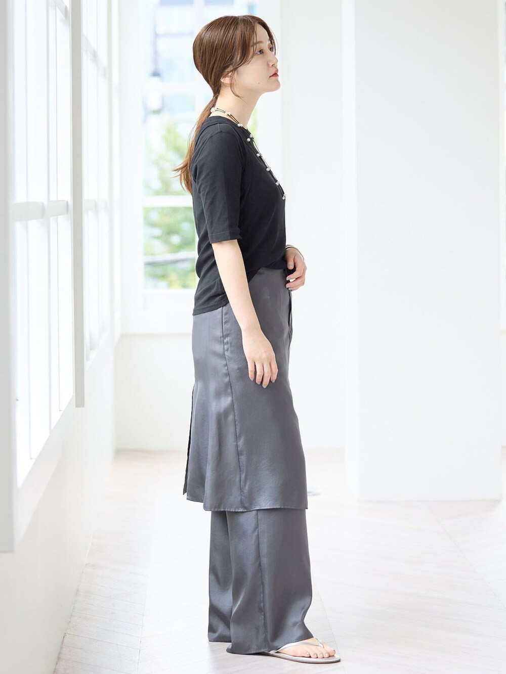 グレー系のその他パンツ、ブラック系のTシャツ/カットソー、シルバー系のサンダルを着用したレディースの夏コーディネートの2枚目の写真