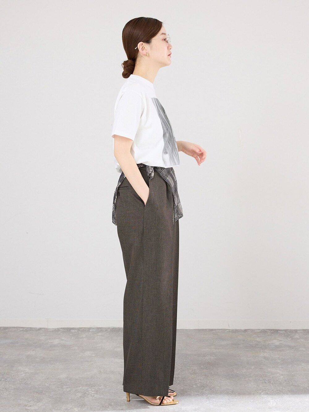 ブラウン系のスラックス、ホワイト系のTシャツ/カットソー、ブラック系のサンダルを着用したレディースの春コーディネートの2枚目の写真