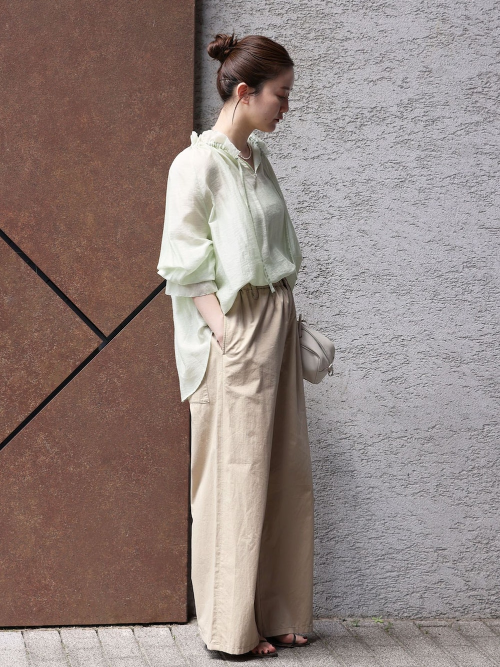 ベージュ系のその他パンツ、グリーン系のシャツ/ブラウス、ホワイト系のショルダーバッグを着用したレディースの春コーディネートの2枚目の写真