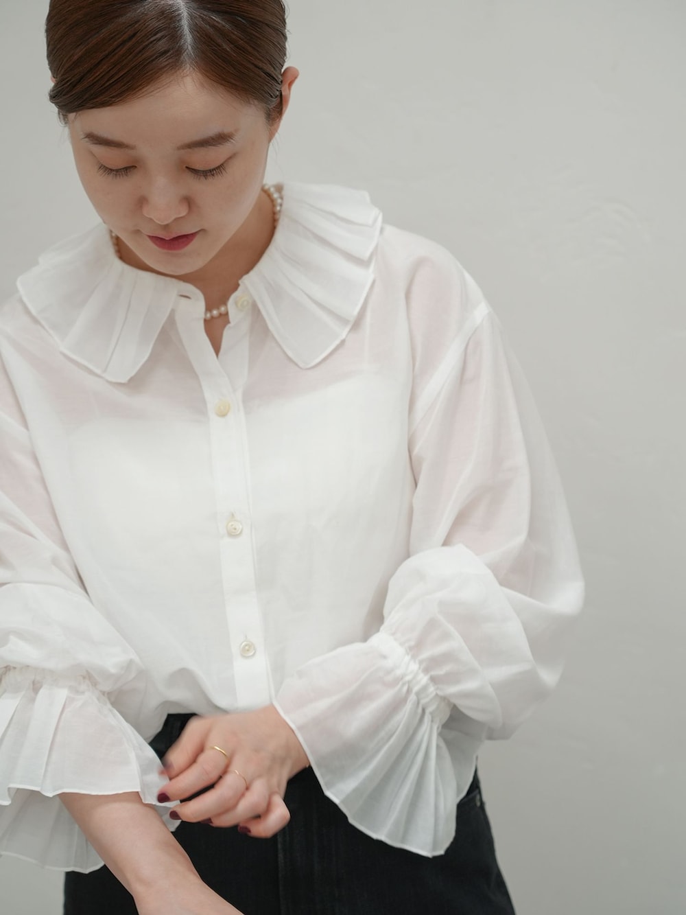 ブラック系のデニムパンツ、ホワイト系のシャツ/ブラウス、グレー系のニット/セーターを着用したレディースの秋コーディネートの2枚目の写真