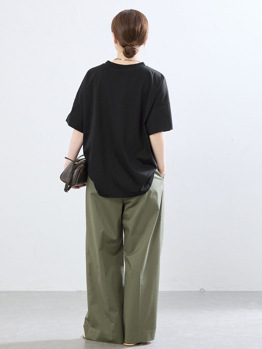グリーン系のチノパンツ、ブラック系のTシャツ/カットソー、ゴールド系のサンダルを着用したレディースの夏コーディネートの3枚目の写真