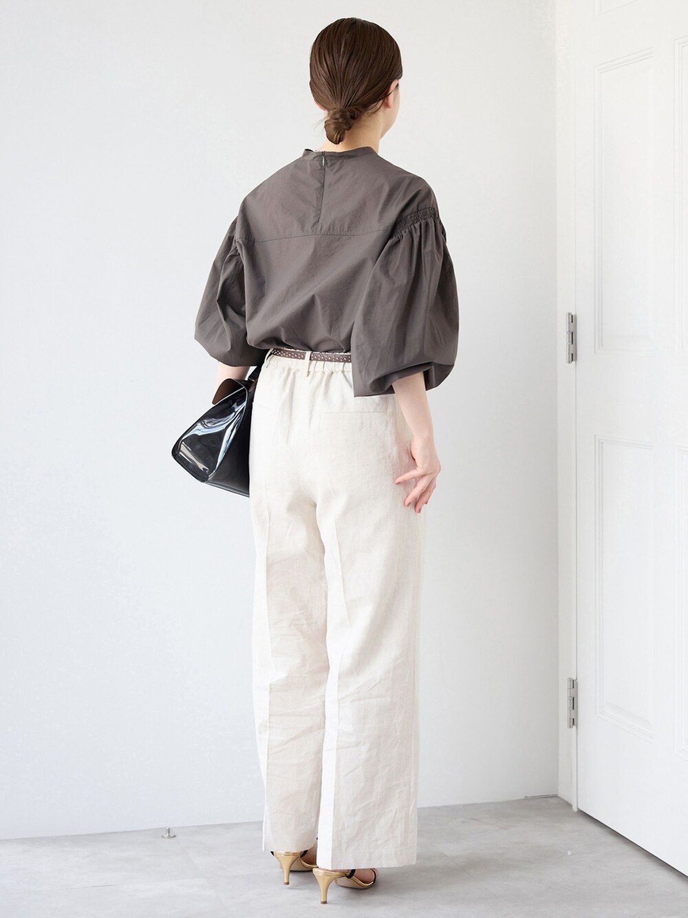 ベージュ系のスラックス、グレー系のシャツ/ブラウス、ブラック系のサンダルを着用したレディースの春コーディネートの3枚目の写真