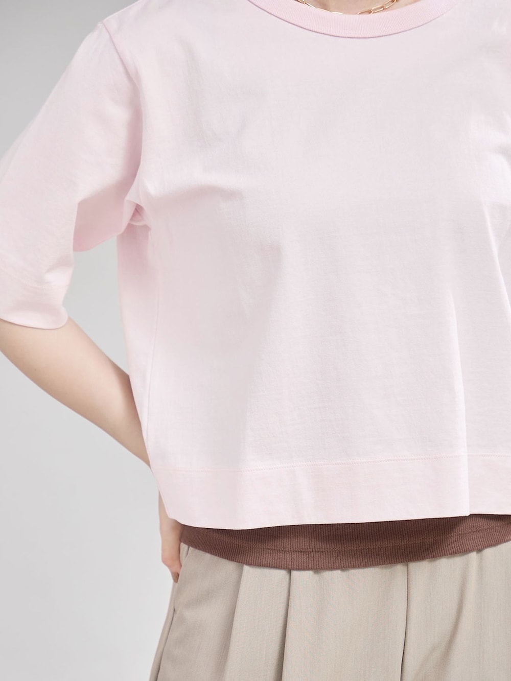 ベージュ系のスラックス、ピンク系のTシャツ/カットソー、ブラウン系のサンダルを着用したレディースの夏コーディネートの5枚目の写真