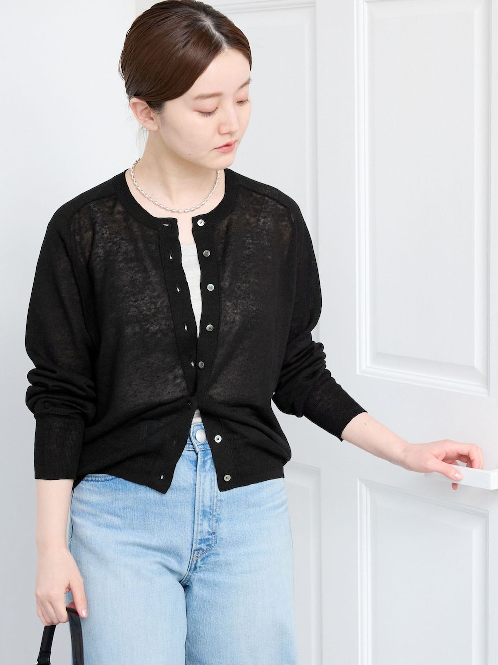 ブルー系のデニムパンツ、ブラック系のカーディガン/ボレロを着用したレディースの春コーディネートの3枚目の写真