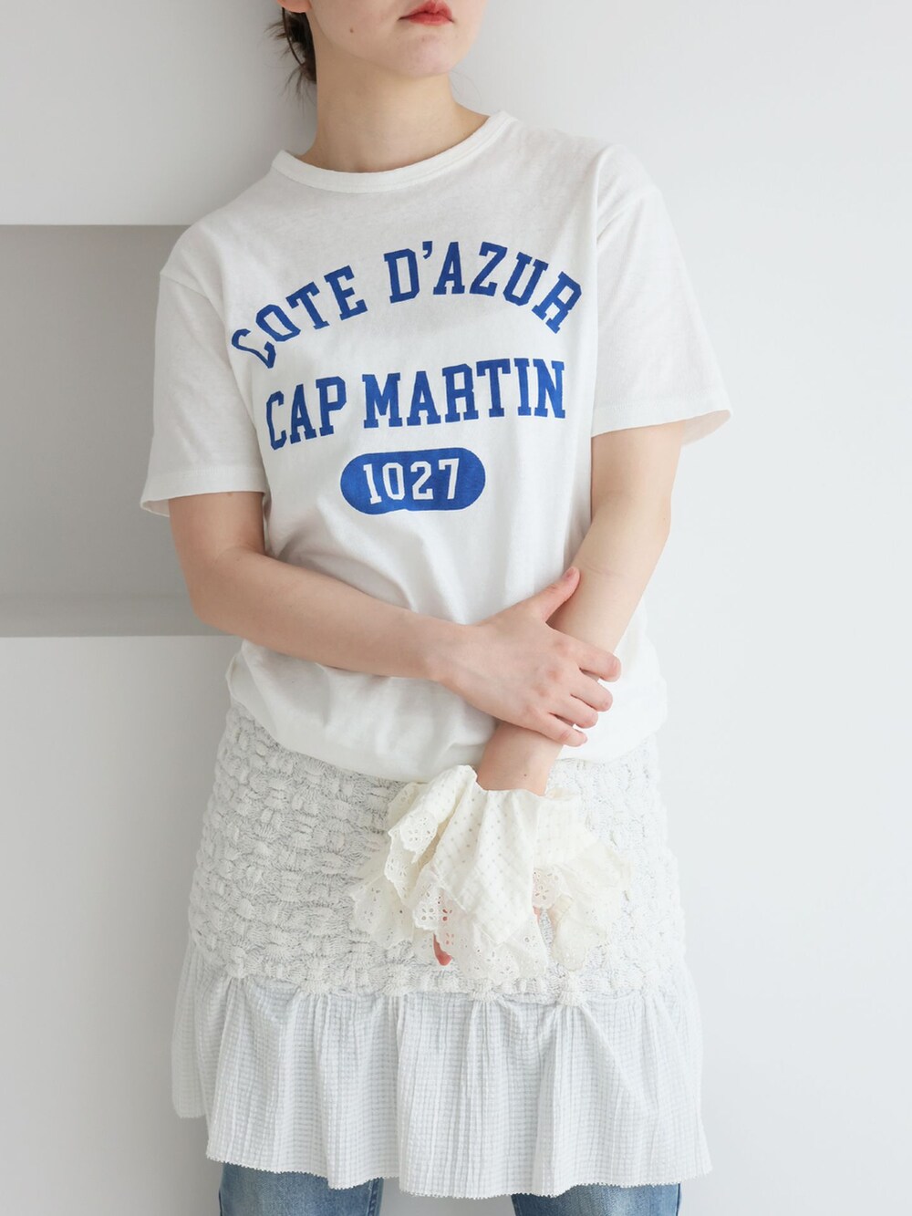 ブルー系のデニムパンツ、ホワイト系のスカート、ホワイト系のTシャツ/カットソーを着用したレディースの春コーディネートの4枚目の写真