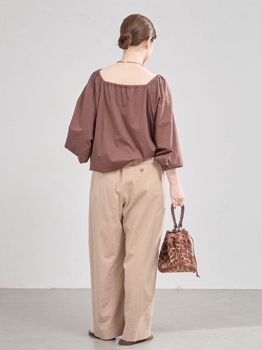 ベージュ系のスラックス、ブラウン系のTシャツ/カットソー、ブラウン系のサンダルを着用したレディースの夏コーディネートの3枚目の写真