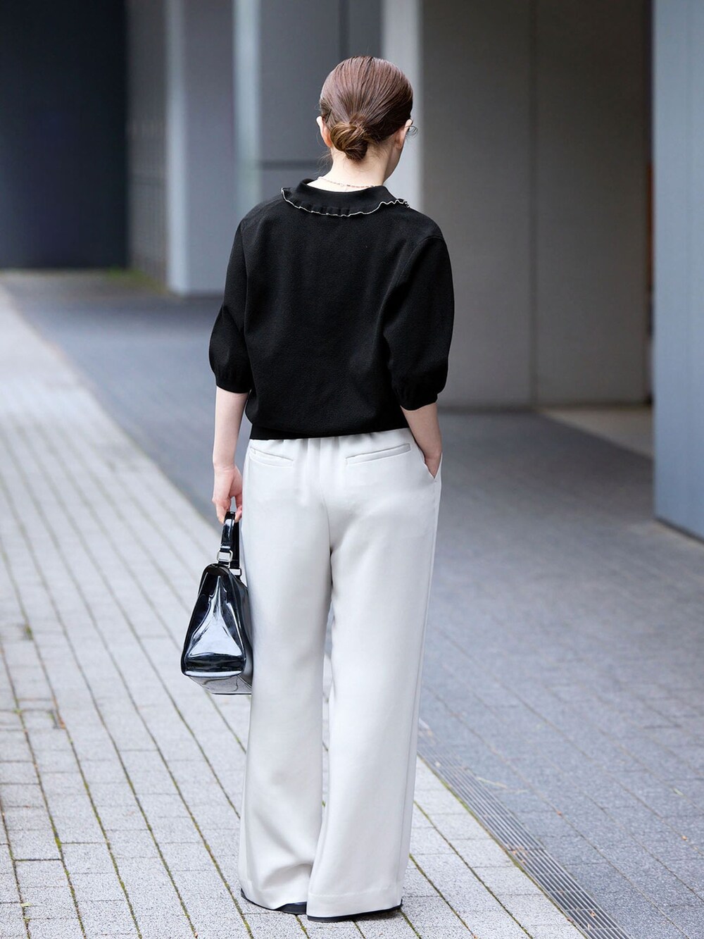 ベージュ系のその他パンツ、ブラック系のニット/セーター、ブラック系のサンダルを着用したレディースの春コーディネートの3枚目の写真